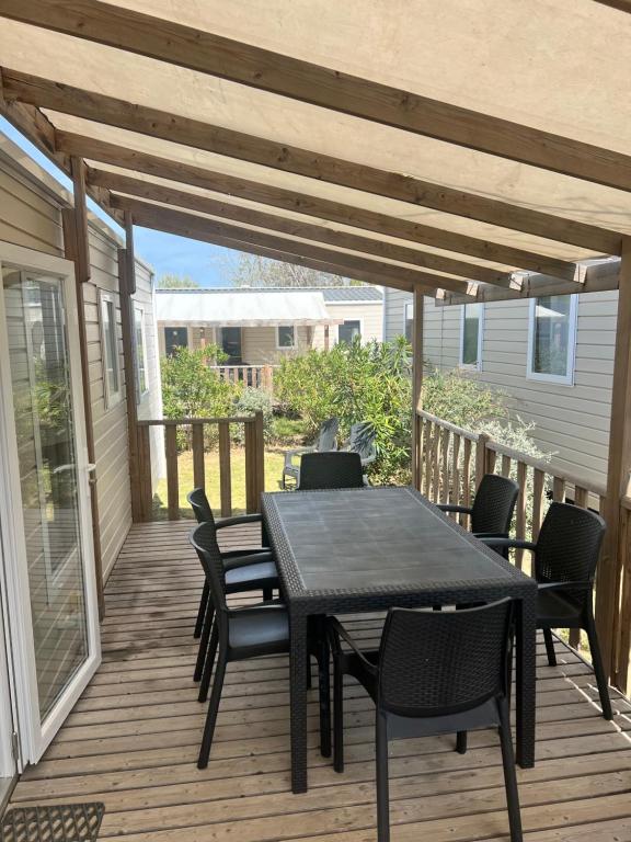 a patio with a table and chairs on a deck at Mobil home Camping 4* La Falaise Narbonne Plage in Narbonne-Plage
