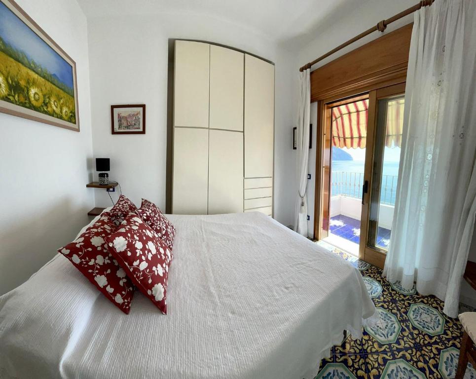 una camera da letto con un letto bianco con cuscini rossi di Suite Capri a Ischia