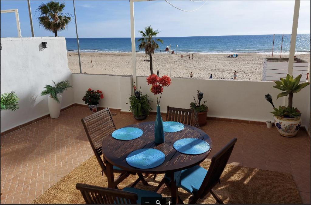 einen Holztisch mit Stühlen und Strandblick in der Unterkunft AMAZING FRONTAL BEACH APARTMENT #Traveller's Awards2023 in Cádiz