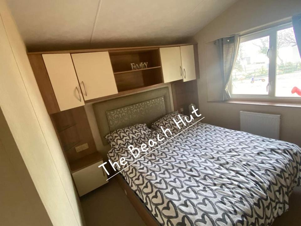 ein Schlafzimmer mit einem Bett in einem Zimmer mit einem Fenster in der Unterkunft The Beach Hut on Lyons Winkups Holiday Park in Kinmel Bay