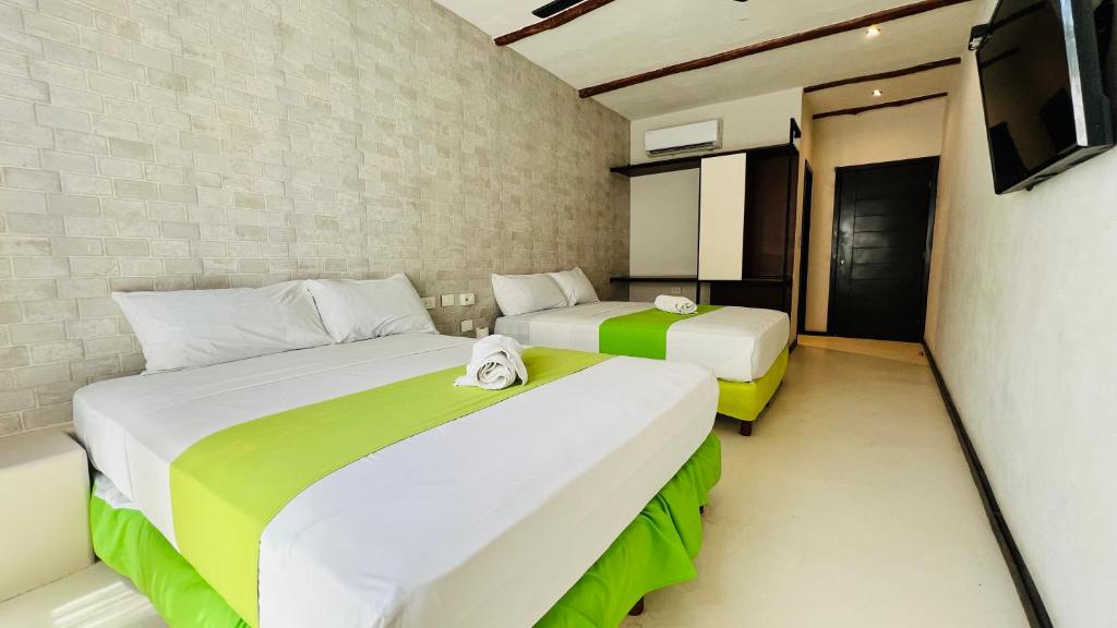 twee bedden in een kleine kamer met een tv bij Hotel MAYARI Holbox in Holbox Island