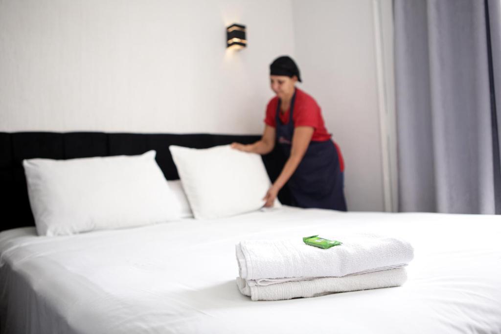 een vrouw naast een bed met handdoeken erop bij Hotel Recanto do Sossego in Uberlândia