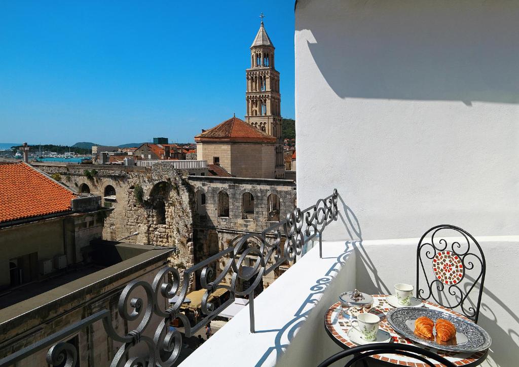 un balcón con mesa y sillas y una torre del reloj en La Porta Luxury Rooms en Split