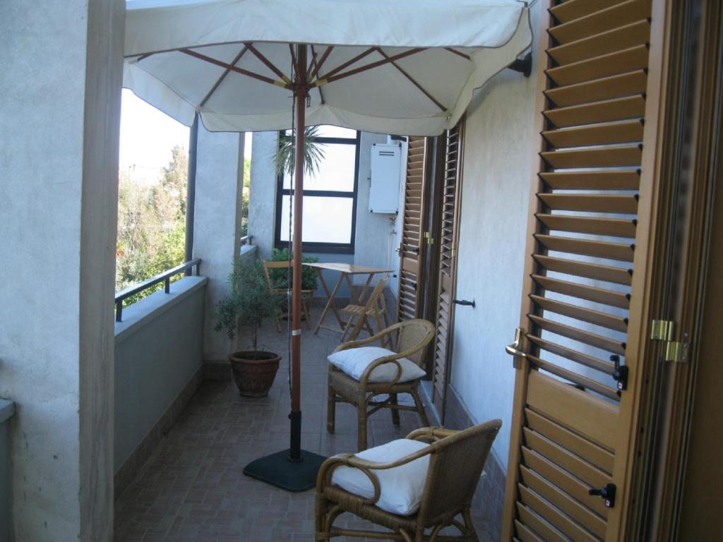 a balcony with an umbrella and chairs and a table at Appartamento le castagnelle in Copersito