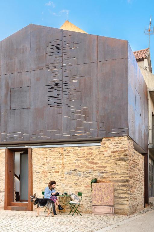 a woman with a dog in front of a building at Casa do Ferreiro in Macedo de Cavaleiros