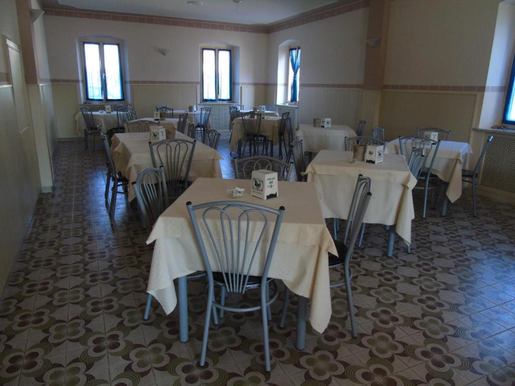 jadalnia z białymi stołami, krzesłami i oknami w obiekcie Albergo Grifone 1891 w mieście Peschiera del Garda