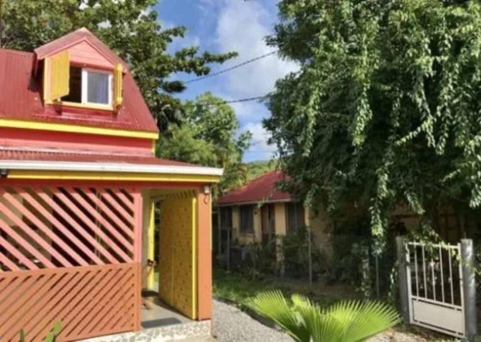 ein Haus mit rotem Dach und einem Zaun in der Unterkunft Maison colibri in Les Anses-dʼArlets