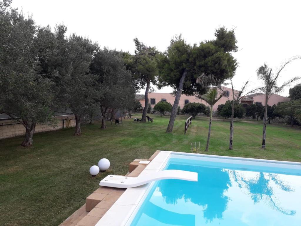 a swimming pool in a yard with trees at Peri peri room in Siracusa