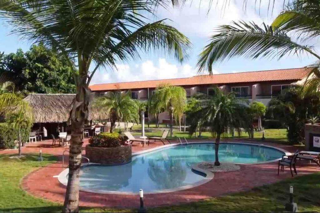 Blick auf das Resort mit Pool und Palmen in der Unterkunft Amazing 2-Bedroom Townhouse near Eagle Beach in Palm-Eagle Beach
