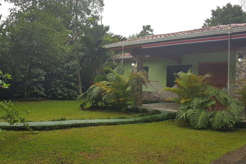 a house with a grass yard in front of it at Arenal ginger home in Fortuna