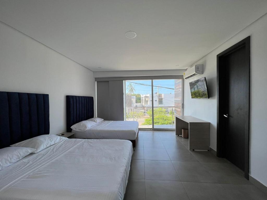 a hotel room with two beds and a window at Hotel Emerawaa Centro Historico in Ríohacha