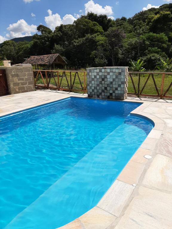 una piscina con acqua blu in un cortile di Chalés e Camping Taquaral a São Thomé das Letras