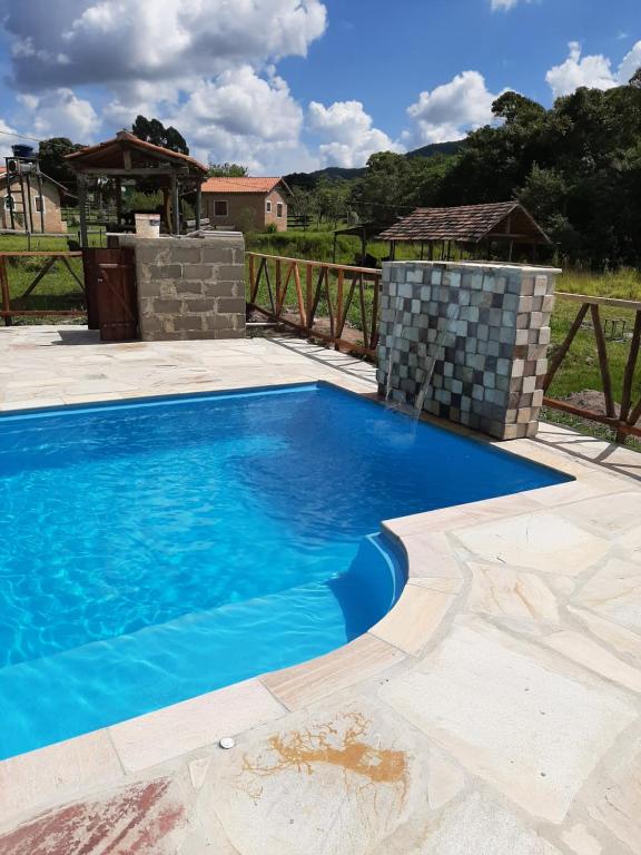 a swimming pool with blue water in a yard at Chalés e Camping Taquaral in São Thomé das Letras