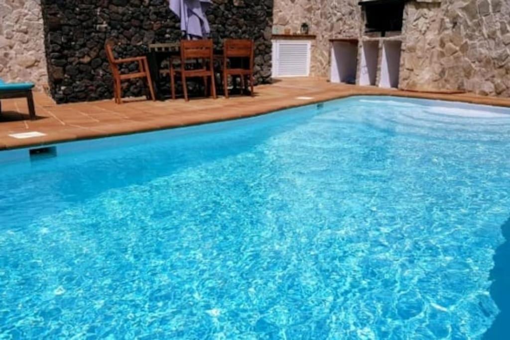 a large blue swimming pool with a table and chairs at LANZATE! in Tinajo
