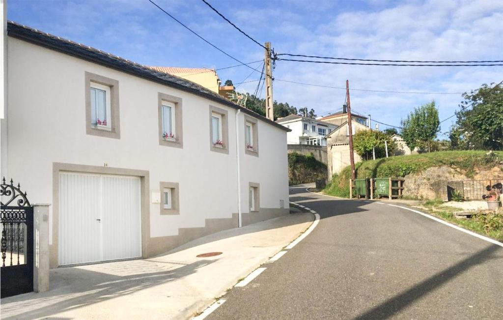 a white house with a garage on the side of a street at Awesome Home In Ortigueira With Wifi in Ladrido