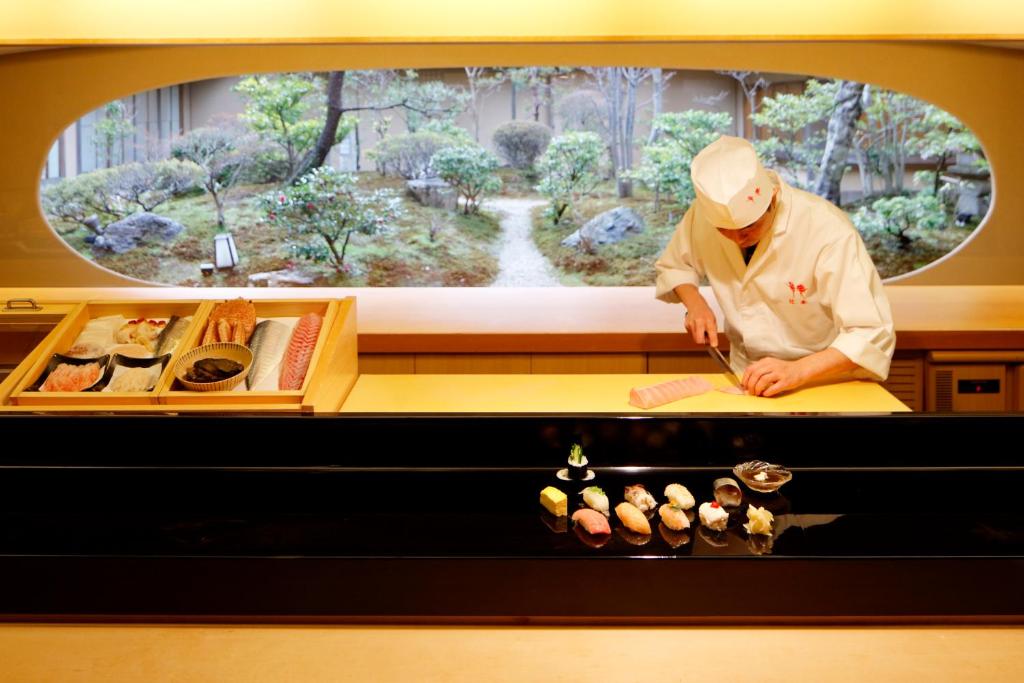 a chef preparing food in front of a window at Hotel Nikko Kanazawa in Kanazawa