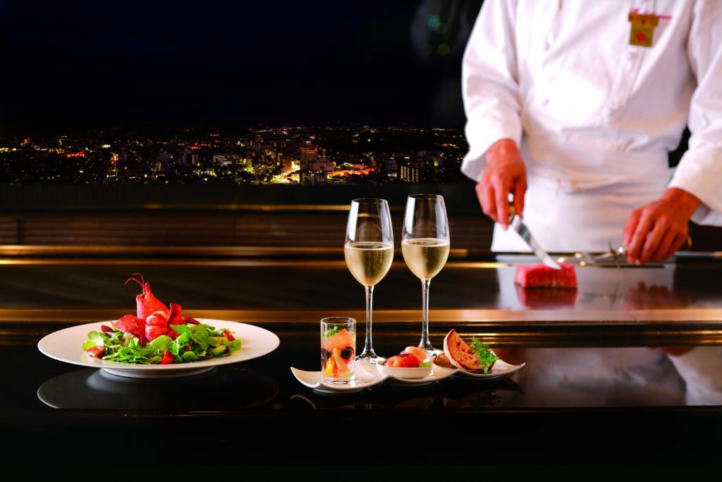 a chef preparing food on a table with glasses of wine at Hotel Nikko Kanazawa in Kanazawa