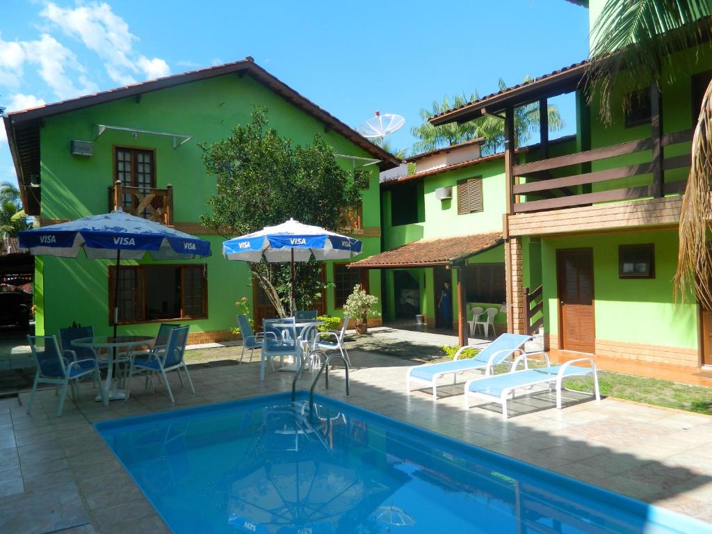una piscina frente a una casa con sillas y sombrillas en Pousada Flor de Paraty, en Paraty