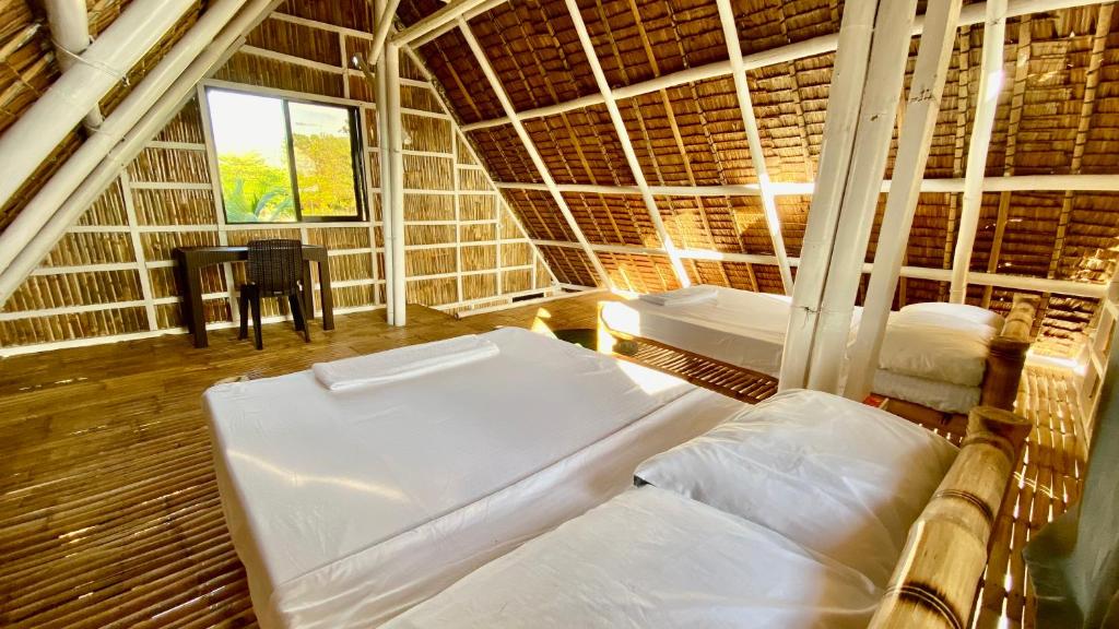 a room with two beds and a table in it at Villa Eliza Ecofarm in Tibiao