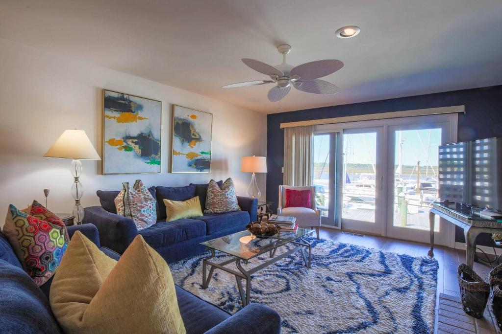 a living room with a blue couch and a ceiling fan at Bohicket Marina Condo in Seabrook Island