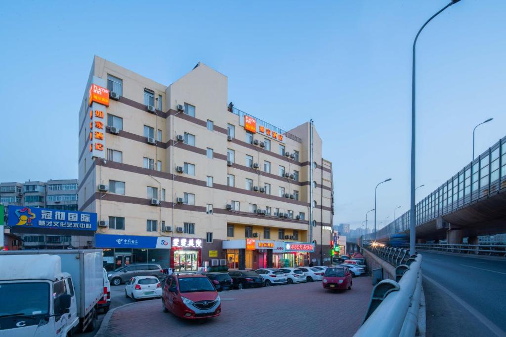 un gran edificio con coches aparcados en una calle de la ciudad en Home Inn Dalian North Railway Station, en Dalian