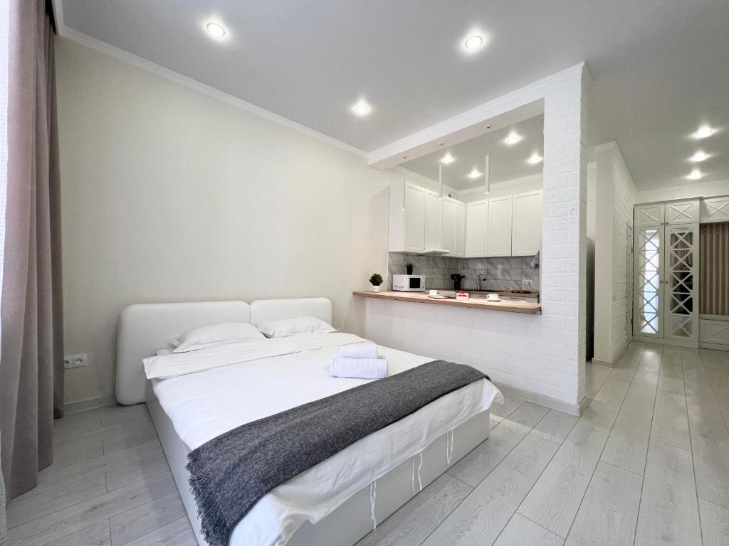 um quarto branco com uma cama grande e uma cozinha em Апартаменты в элитном ЖК em Pavlodar