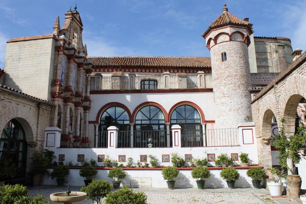 un edificio con una torre y un castillo en El Palacio de San Benito, en Cazalla de la Sierra