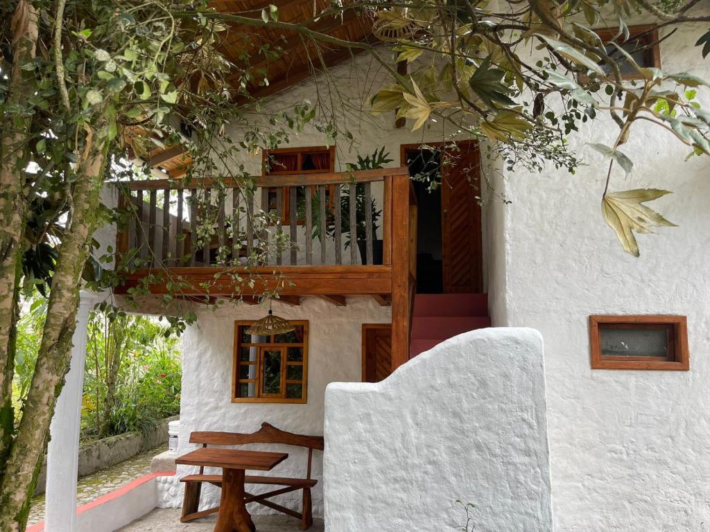 ein Haus mit einem Holzbalkon und einem Holztisch in der Unterkunft Casa Museo - Naturaleza y Tradición in Otavalo