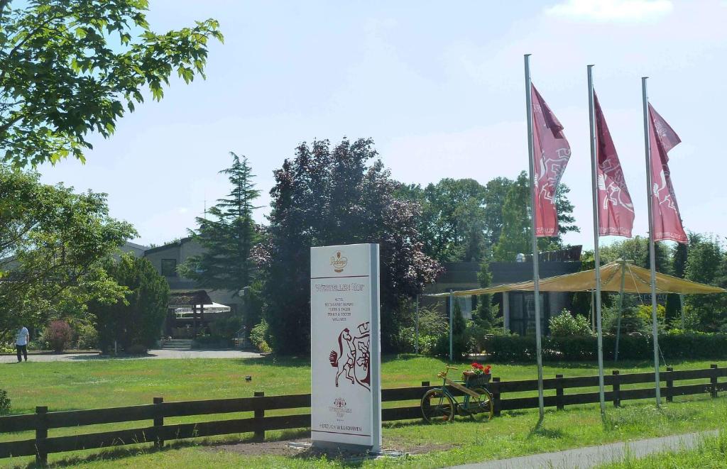 un panneau dans l'herbe à côté d'une clôture avec drapeaux dans l'établissement Hotel Westfalen Hof, à Rahden