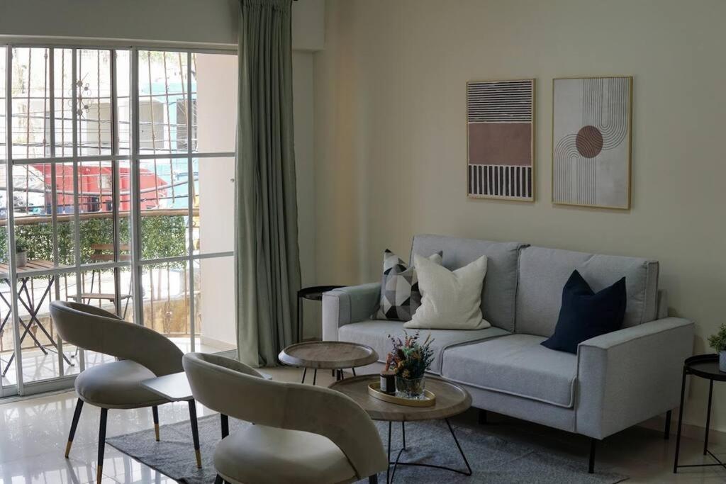 uma sala de estar com um sofá, uma mesa e cadeiras em Hermoso Apartamento Cerca de la Embajada Americana em Santo Domingo