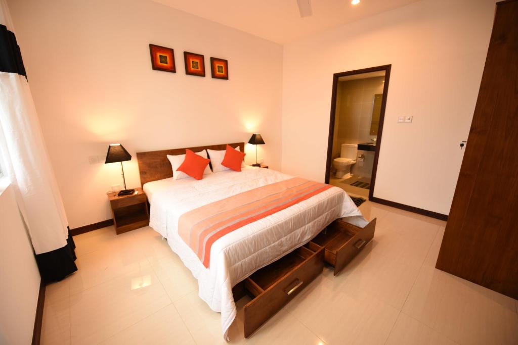 a bedroom with a large bed with orange pillows at OnThree20 Araliya Apartment Colombo in Colombo