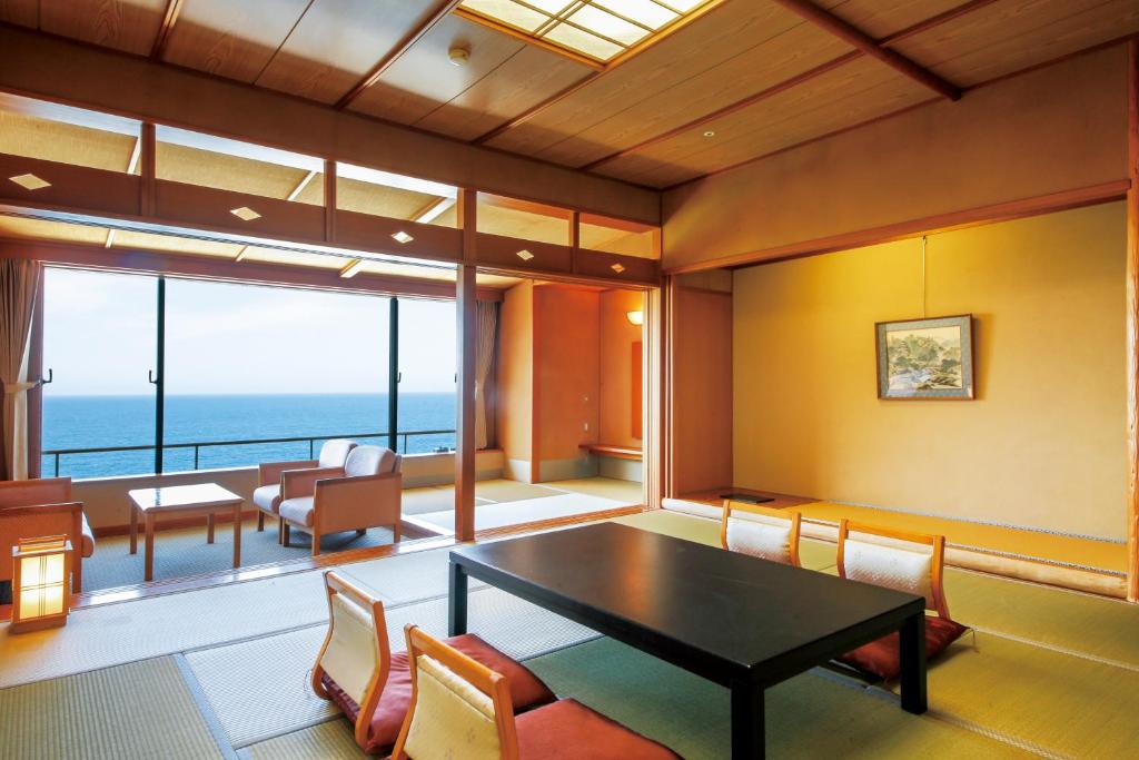 a room with a table and chairs and the ocean at Hotel Kinparo in Toyooka