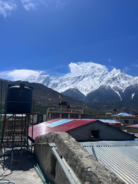 una sedia seduta in cima a un tetto con montagne innevate di Hotel Dancing Yak a Jomsom