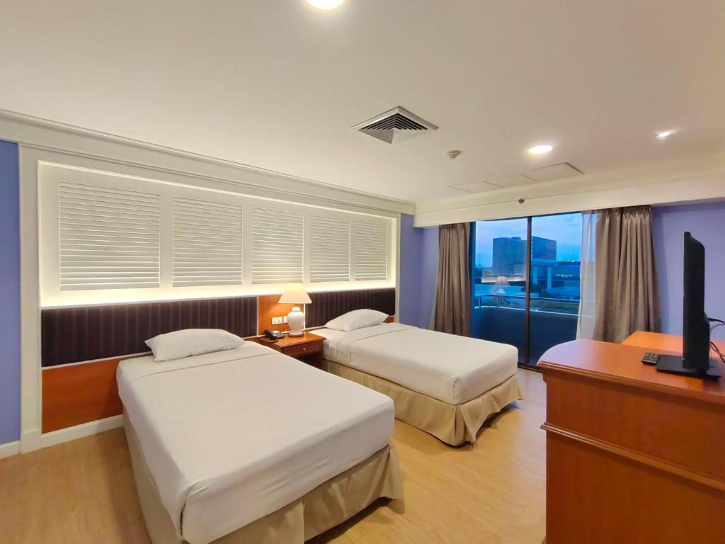 バンコクにあるEbina House - SHA Extra Plusのベッド2台とテレビが備わるホテルルームです。