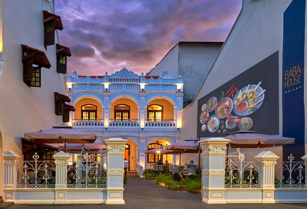 a blue building with a balcony with tables and umbrellas at Baba House Melaka in Melaka