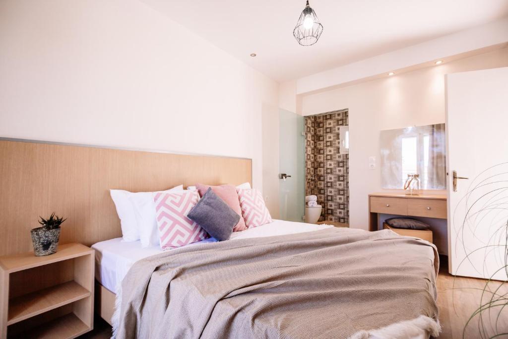 a bedroom with a bed with pink and grey pillows at Villy Suites in Argasi