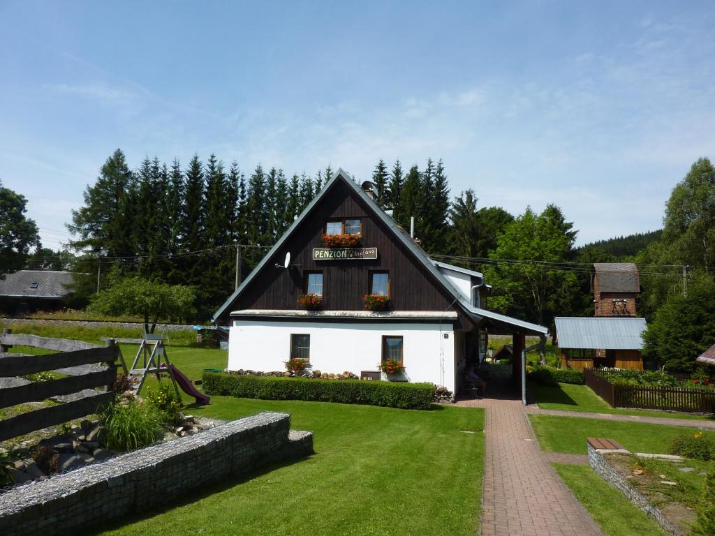 una pequeña casa blanca con techo negro en PENZION U ŠTEFANA en Ostružná