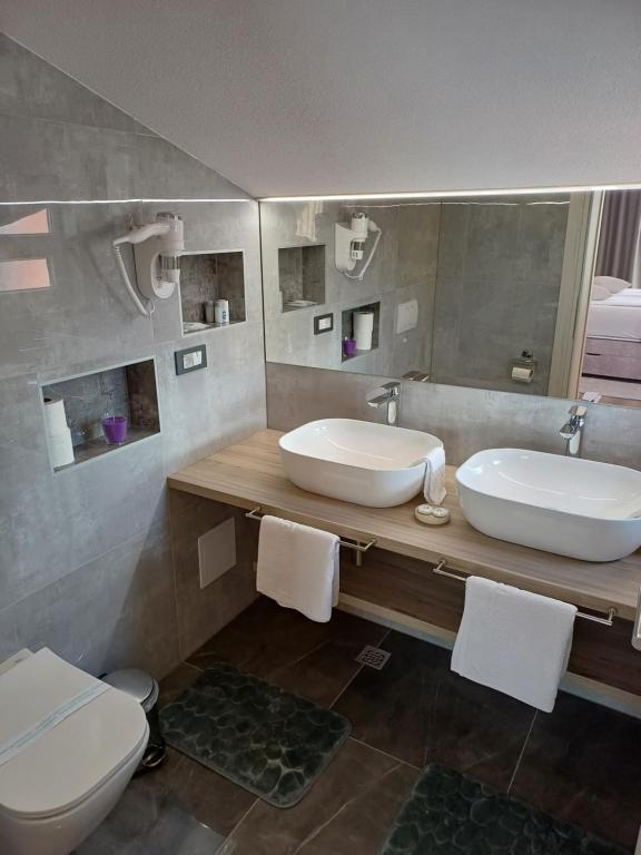 a bathroom with two sinks and a toilet and a mirror at Apartments Jakšić in Trogir