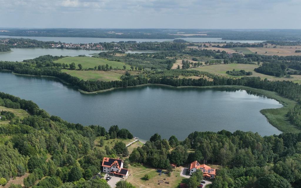 an aerial view of a lake with houses and trees at Hosteria na Mazurach in Dąbrówno