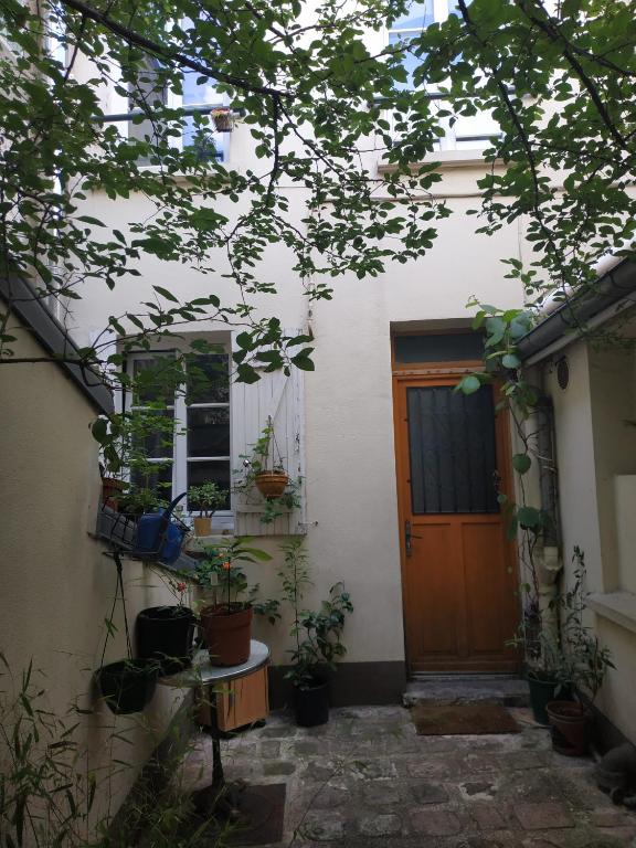 une maison avec des plantes en pot devant une porte dans l'établissement Maison de ville à 10 minutes de Paris, à Nanterre