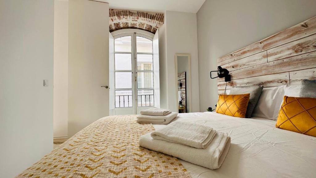 a bedroom with a large bed with two towels on it at Apartamentos GADIR CENTRO in Cádiz