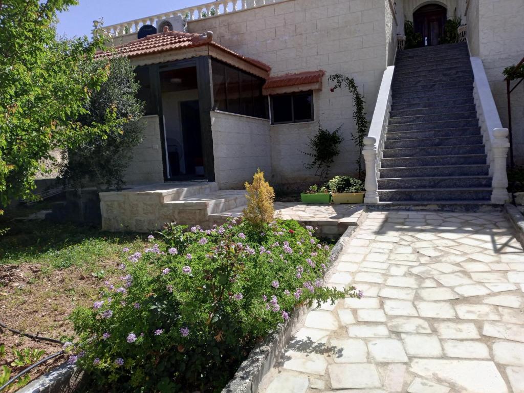 una casa con escaleras y flores delante en family studio en Wadi Musa