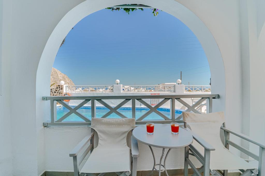 een tafel en stoelen op een balkon met uitzicht op de oceaan bij M.G. Hotel Studio & Apts in Perissa