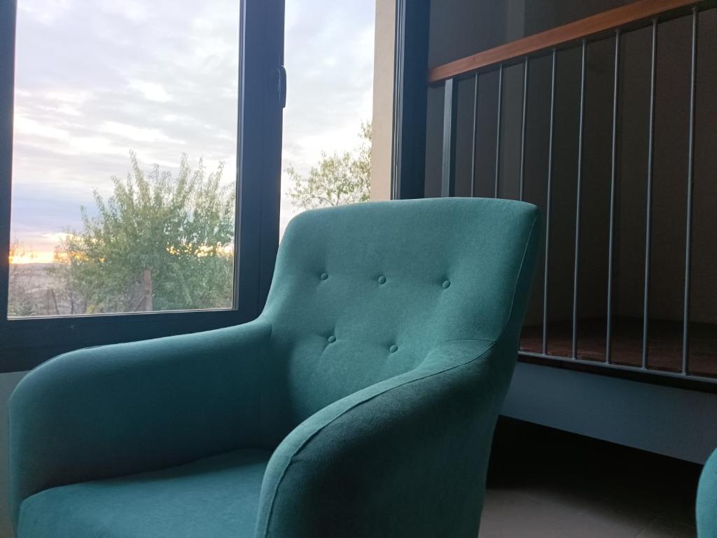 une chaise verte assise devant une fenêtre dans l'établissement Albergue El Muro, 