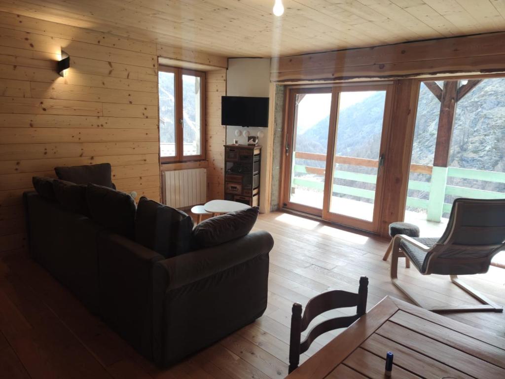 a living room with a couch and chairs and windows at Les Hauts du Roux in Abriès