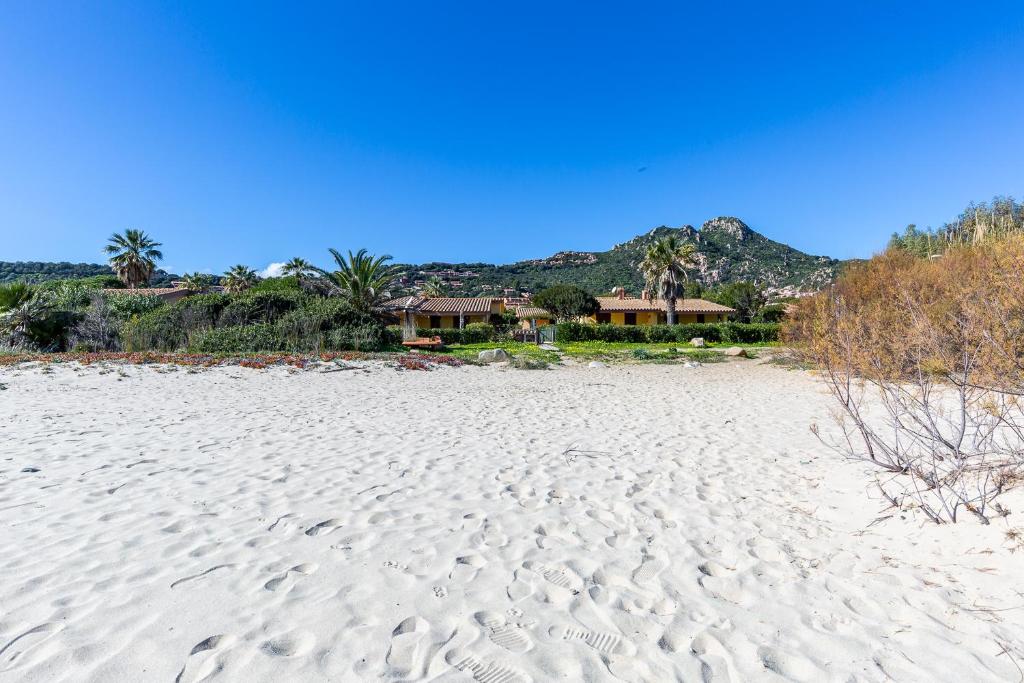 una playa de arena blanca con casas en el fondo en Villetta Pino, en Costa Rei