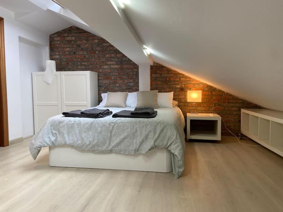 ein Schlafzimmer mit einem Bett und einer Ziegelwand in der Unterkunft Loft en calle emblemática in Santander