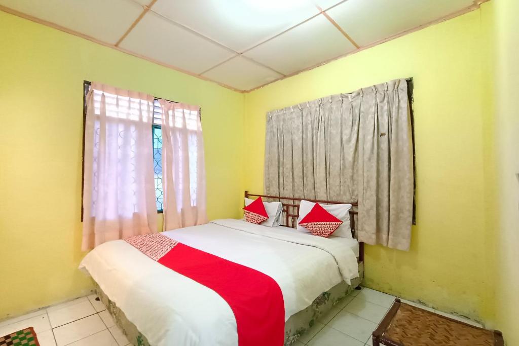 Schlafzimmer mit einem Bett mit roten und weißen Kissen in der Unterkunft OYO 92503 Penginapan & Villa Sirait in Parapat
