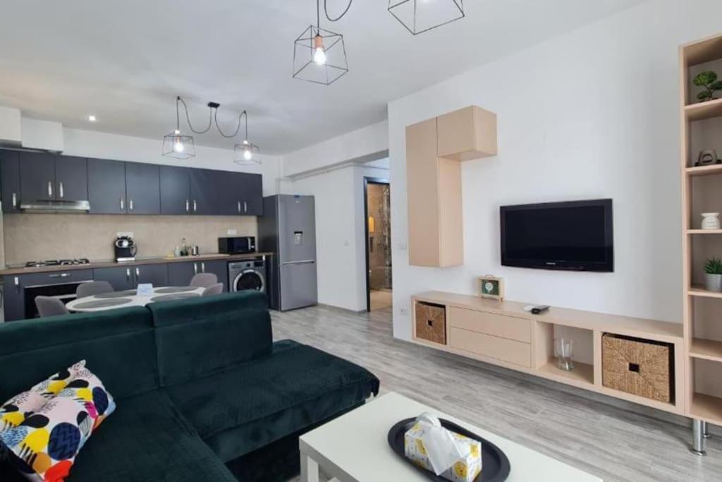 a living room with a green couch and a kitchen at Emerald Apartment Mamaia Nord in Năvodari