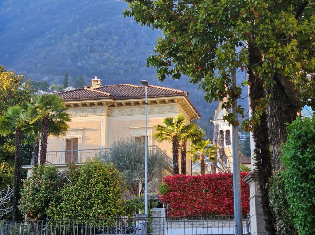 a white house with palm trees in front of it at Villa by @ Home Hotel Locarno in Locarno